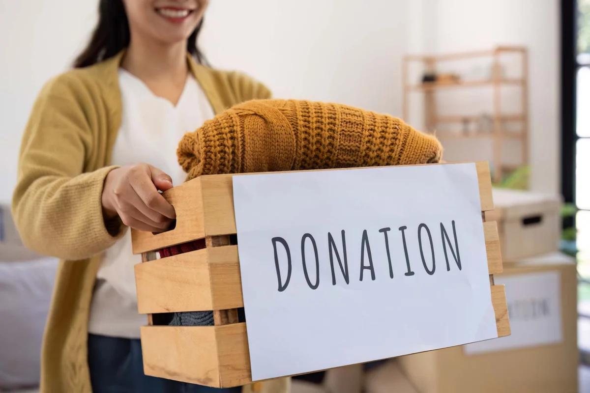 Volunteer holding a wooden crate labeled Donation