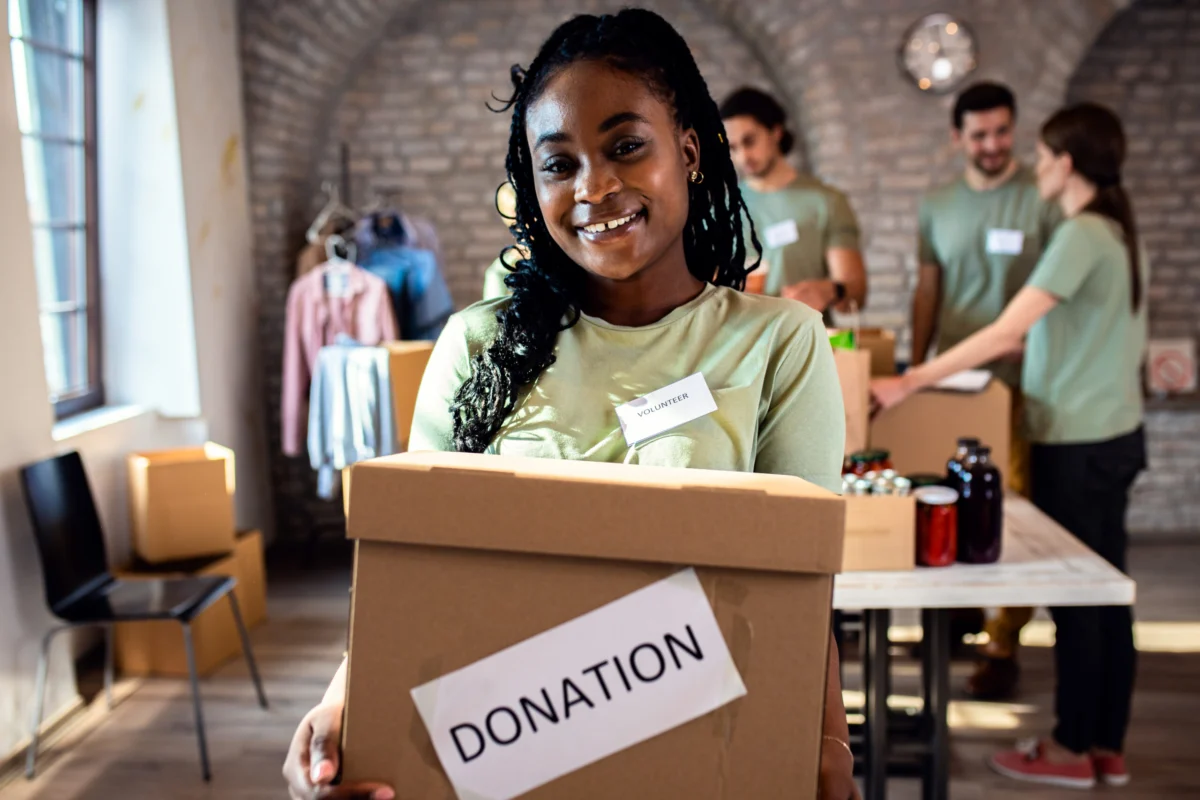 Volunteer carrying a cardboard box labeled Donation