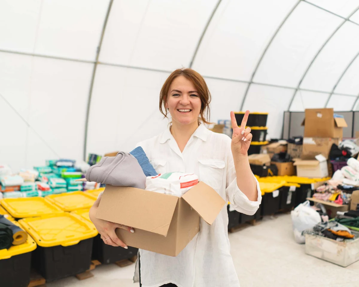 Volunteer holding a box of donations in a sorting area